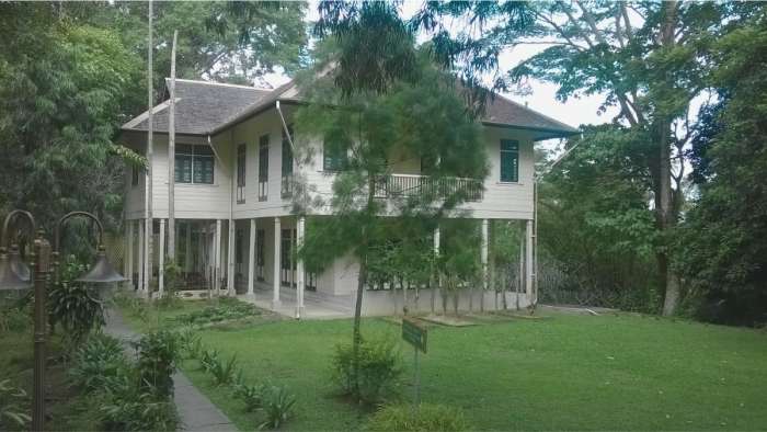 Historic two-story wooden colonial house surrounded by lush green foliage at the Agnes Keith estate in Sandakan, Sabah, Borneo.