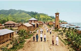 A captivating historical view depicting early 20th-century Jesselton (now Kota Kinabalu), North Borneo. The image features local residents and British colonial officials walking down a dirt main street lined with traditional wooden structures, with the iconic wooden Atkinson Clock Tower standing prominently along the coastal harbor against a background of terraced hills.