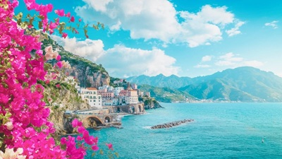 Vibrant modern panoramic view of Atrani village on the Amalfi Coast with bright pink bougainvillea flowers in the foreground.