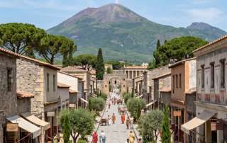 An atmospheric historical reconstruction displaying a bustling 1st-century Roman market street looking toward a peaceful Mount Vesuvius before the 79 CE disaster, used as an immersive visual for readers of historical fiction author Don Peter.