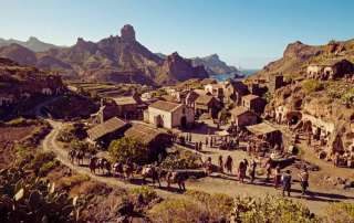 Featured artwork for a Gran Canaria road trip guide, showcasing a historic depiction of mountain villages, cave dwellings, and rugged volcanic scenery across the island.