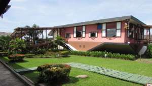 Exterior view of the upside-down house structure surrounded by manicured green lawns and landscaped gardens at Rumah Terbalik Tuaran.