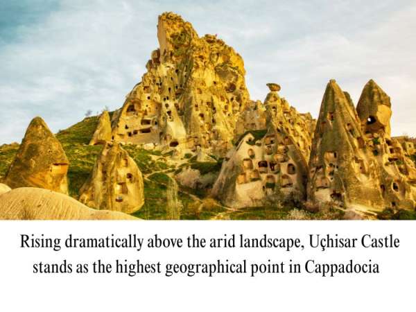 Scenic view of Uçhisar Castle, a towering rock fortress carved with ancient windows and rooms in Cappadocia, Turkey.